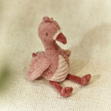 Plush flamingo toy on a textured beige surface