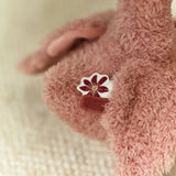 Close-up of a pink fluffy toy with a flower patch on a soft beige background