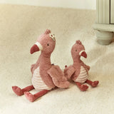 Two plush flamingo toys sitting on a textured surface.