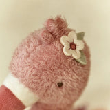 Close-up of a pink plush toy with a flower detail on a beige background