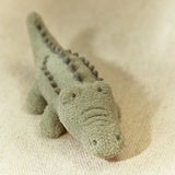 Plush toy alligator on a beige fabric background