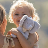 Child holding a plush elephant toy with a blurred natural background