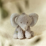 Plush elephant toy on a textured beige surface