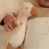 Child holding a plush goose toy with a soft background