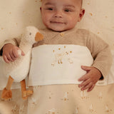 Baby holding a plush goose toy with a matching outfit featuring duck designs.