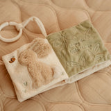 Two soft toys, one with a bunny design and the other with leaf patterns, on a quilted surface.