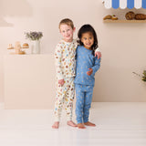 Two children wearing pajamas standing in a room with a shelf in the background.