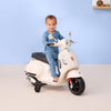 Child on a toy scooter against a light blue wall
