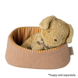 Dog bed with a plush dog toy inside on a white background