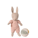 Stuffed rabbit toy in pink outfit with a ball on a white background