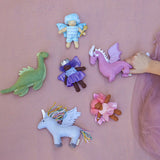 Collection of colorful fairy and dragon toys on a pink surface