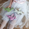 Child holding three soft toy animals against a white tulle skirt.