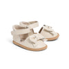 Pair of cream-colored baby sandals with bow details on a white background