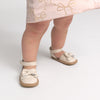 Child wearing beige sandals with bow details on a light background