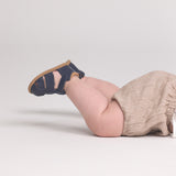 Child wearing navy sandals and beige pants on a light gray background