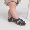 Navy sandals worn by a child on a light background