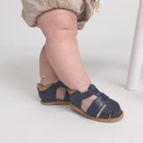 Navy sandals worn by a child on a light background