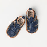 Pair of navy blue sandals with brown soles on a white background