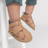 Children's feet wearing tan sandals with velcro straps on a light background