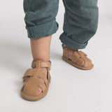 Child wearing brown sandals on a plain background