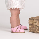 Child wearing pink checkered sandals with a white background