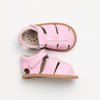 Pair of pink checkered baby shoes with brown soles on a white background