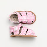 Pair of pink checkered baby shoes with brown soles on a white background