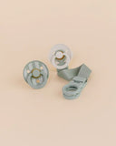 Two pacifiers with a strap on a beige background