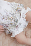 Close-up of a bouquet of flowers held by a person wearing a floral dress.