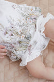 Close-up of a bouquet of flowers held by a person wearing a floral dress.