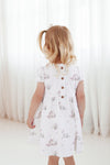 Child wearing a white floral dress with buttons on a white background