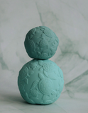 Turquoise stress ball with turtle design on a marble background