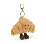 Plush croissant keychain with a smiling face on a white background