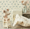 Children's room with floral wallpaper, toy mouse, and floral-patterned blanket.