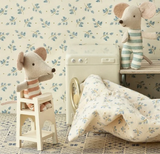 Children's room with floral wallpaper, toy mouse, and floral-patterned blanket.