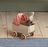 Small toy stroller with a rabbit figure on a wooden floor