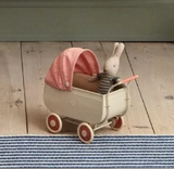 Small toy stroller with a rabbit figure on a wooden floor