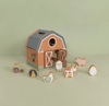 Wooden toy barn with animal figures on a light green background