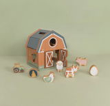 Wooden toy barn with animal figures on a light green background