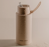 Brown water bottle with droplets on a beige background