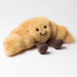 Plush toy resembling a caterpillar with a smiling face on a white background