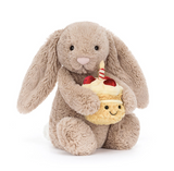 Plush toy rabbit holding a plush cupcake with a candle on a white background