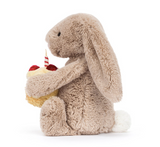 Plush bunny holding a small cake with a candle on a white background
