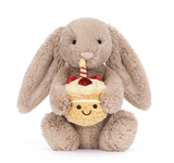Plush toy rabbit holding a cake with a candle on a white background