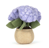 Stuffed toy resembling a purple flower in a beige pot on a white background