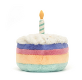 Plush toy resembling a birthday cake with a candle on a white background