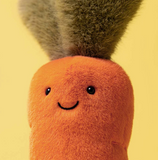 Plush toy carrot with a smiling face on a yellow background