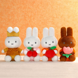 Four plush toy bunnies in different outfits on a beige background