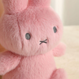 Close-up of a pink plush toy with sad face expression on a blurred background