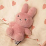Pink plush bunny toy on a soft surface with heart patterns